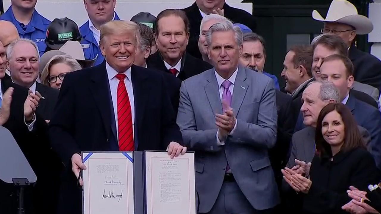 President Trump signs the USMCA into law with senators, administration officials and trade officials by his side.