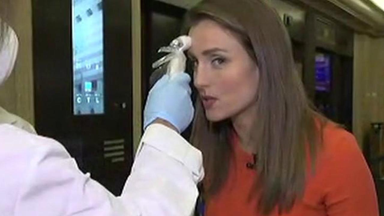 FOX Business’ Kristina Partsinevelos gets her temperature checked at the entrance of the New York Stock Exchange. 